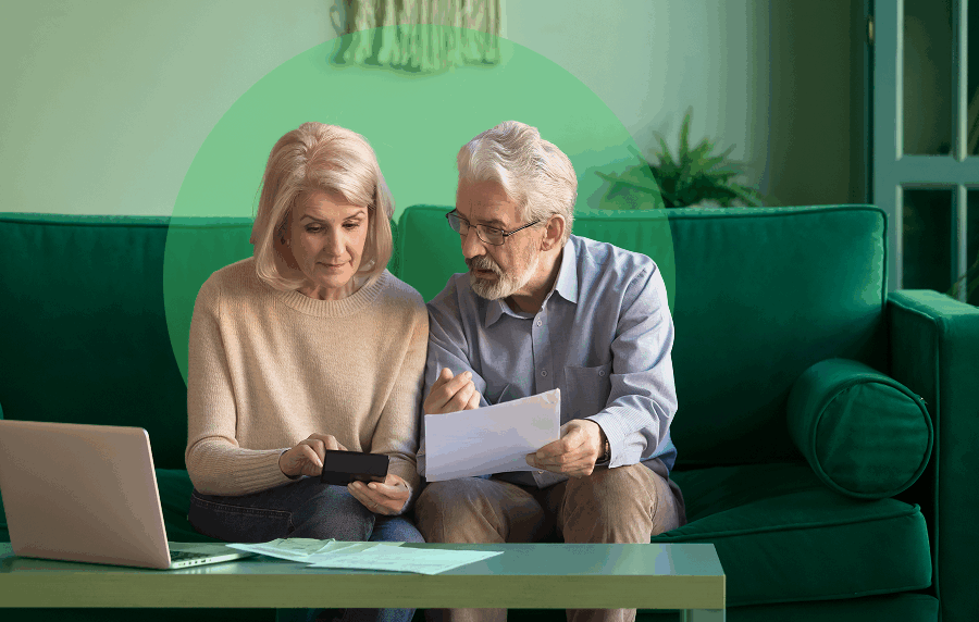 Senior white couple sitting on couch looking at documents together