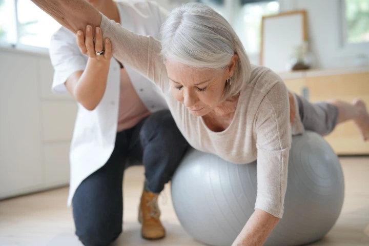 An older woman excerising on a yoga ball