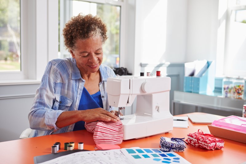 Senior black woman stitching fabric using a sewing machine