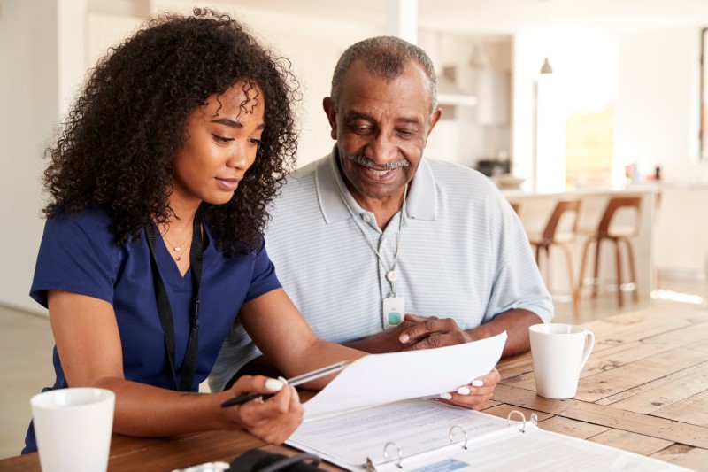 Female healthcare worker checking test results with a senior man during a home health visit