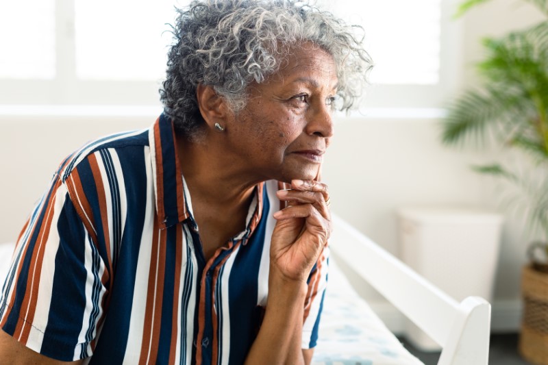 Portrait of thoughtful african american senior woman sitting down at home