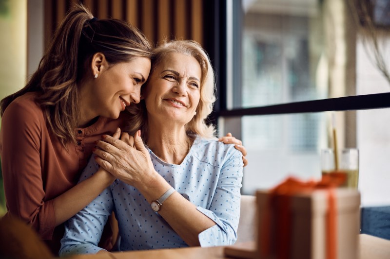 Happy senior woman enjoys in daughter's affection on Mother's day.
