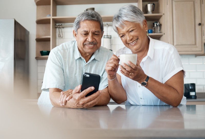 Shot of a senior couple using a phone together at home in their kitchen