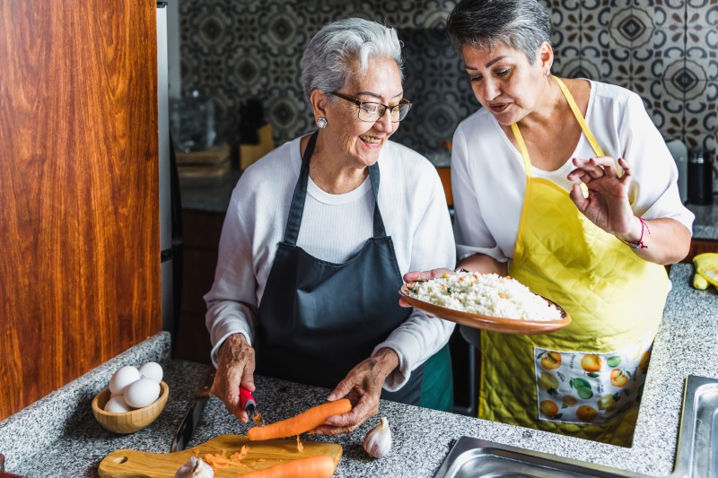 Hispanic women grandmother and daughter cooking together at home in their kitchen