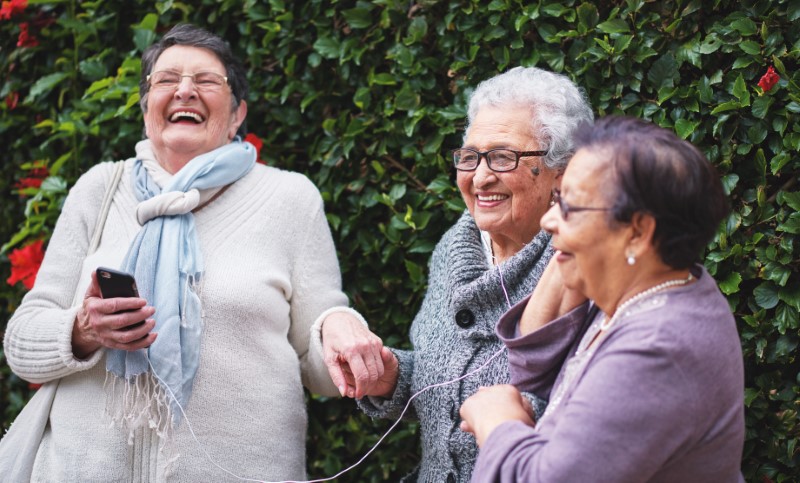 Elderly women listening to music on smartphone wearing earphones and smiling