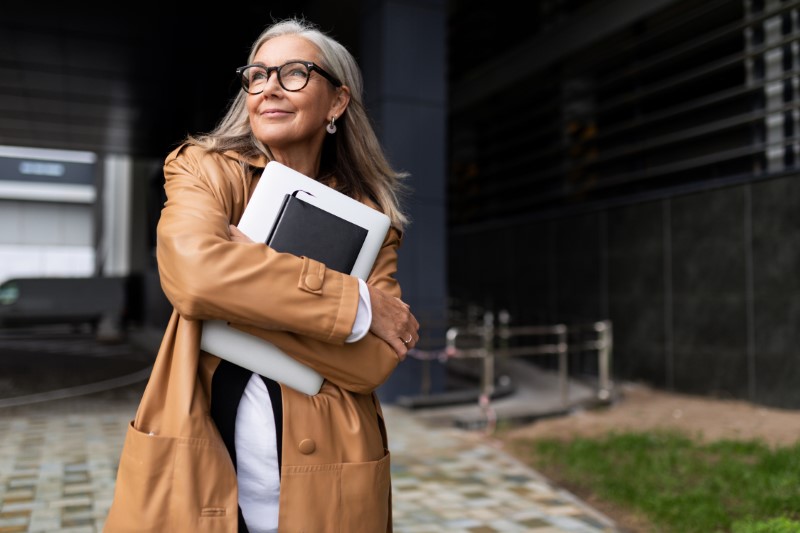 mature businesswoman with a laptop in her hands near a building