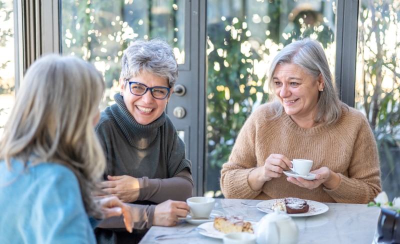 Group of smiling mature women having breakfast together at an outdoor cafe