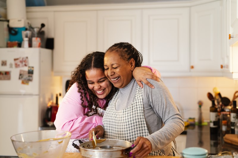 Happy African American mother and daughter preparing a homemade dessert