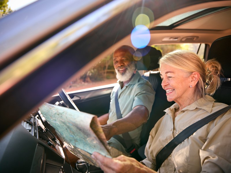 Senior Couple On Day Trip Out Driving In Car Reading Map