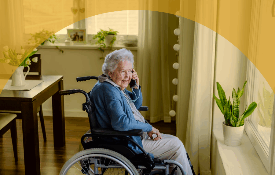 Elderly white woman in wheelchair on cell phone in her home