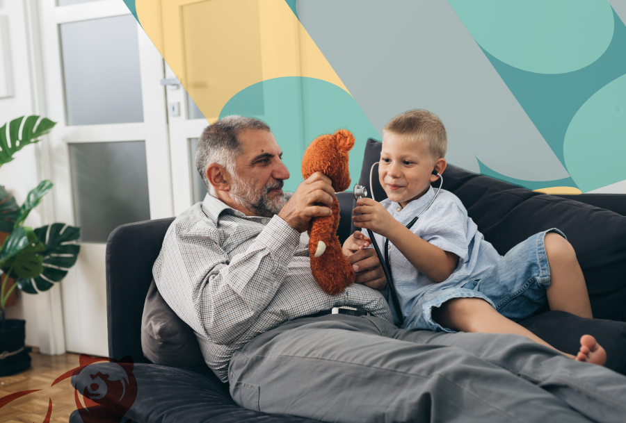 Senior man with medium skin tone holding a stuffed animal, playing on couch with boy who has stethoscope in his ears