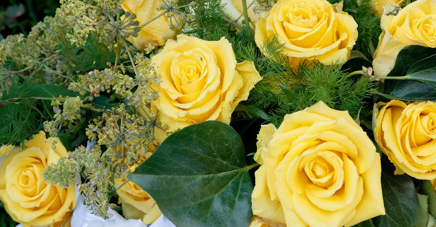 A dense bouquet of yellow roses with leafy fillers.