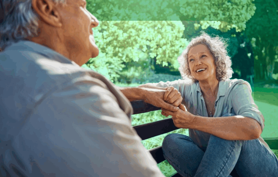 Senior woman and man talking and laughing on a park bench