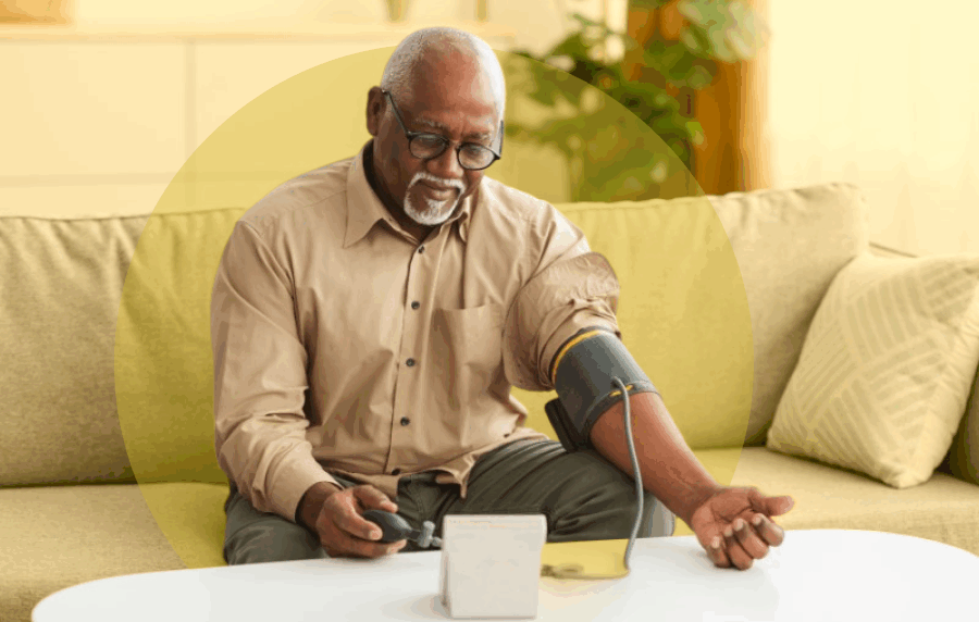 Senior Blank man with white hair and glasses sitting on his couch using a blood pressure monitor