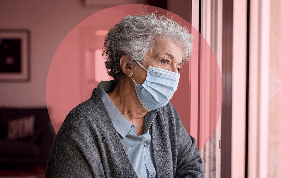 Close-up of white senior woman with short curly white hair in her home, gazing out the window and wearing a surgical mask
