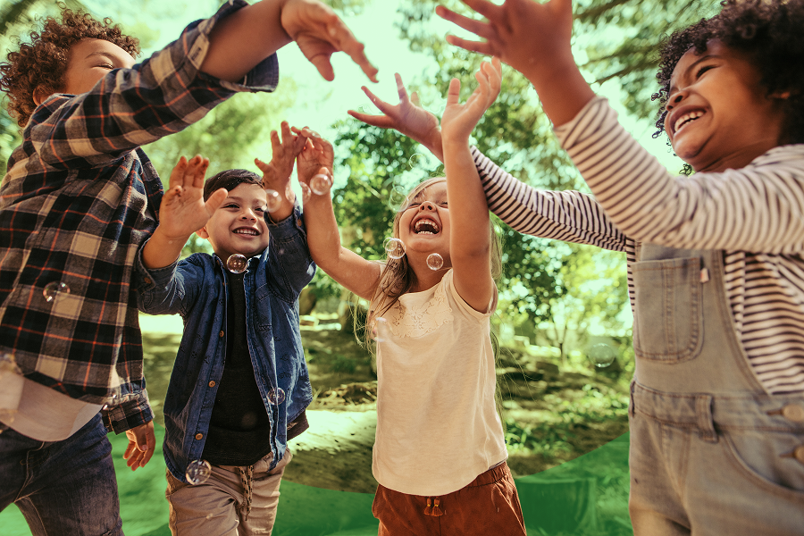 Close-up shot of 4 children playing outside with their hands in a circle
