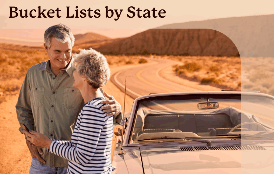 Senior couple with arms around each other, standing next to a convertible parked along a winding rows with a desert and rock formations in the background