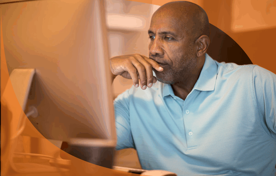 Senior black man looking intently at a comupter monitor