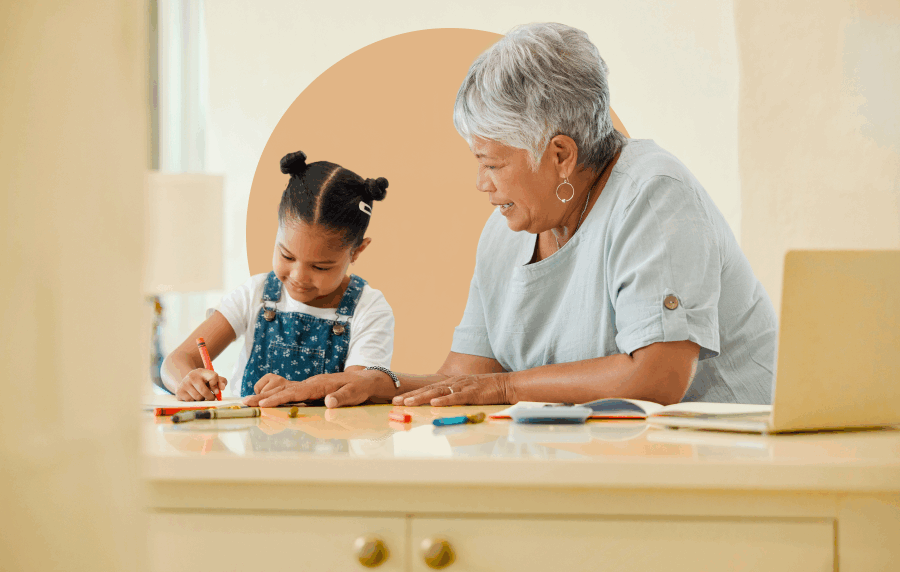 A senior woman and granddaughter coloring together at a table