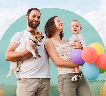 Smiling family with baby, dog, and colorful balloons outdoors