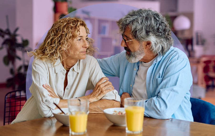 Senior couple sitting and talking seriously over breakfast, their orange juice and cereal sitting in front of them on the table