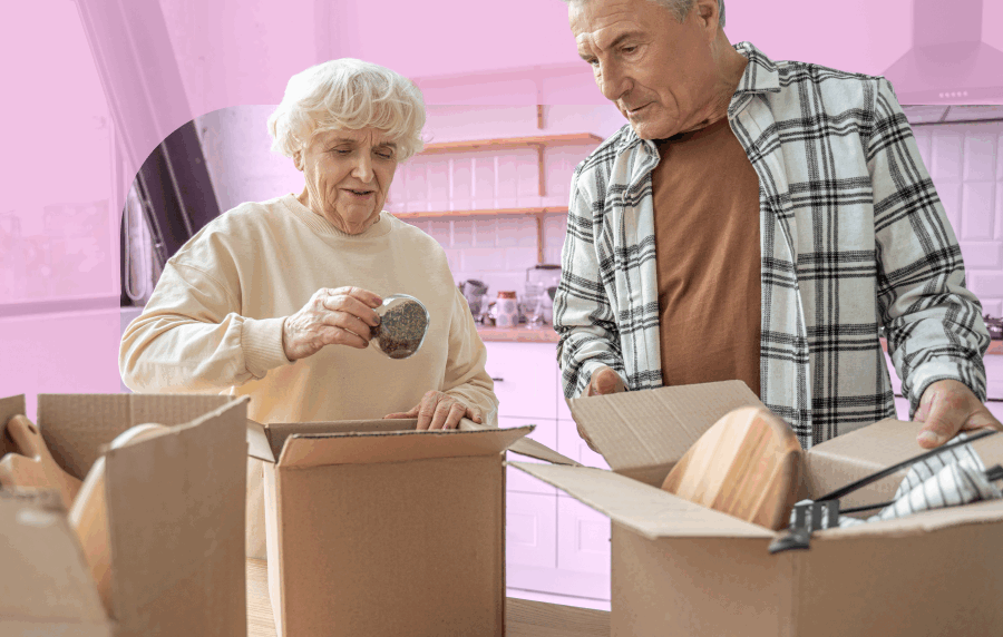 Two seniors, a man and a woman, thoughtfully packing kitchen items into boxes