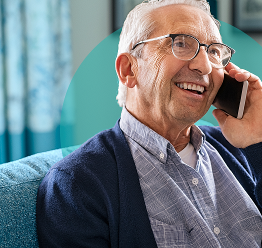 Elderly man smiling while talking on a smartphone indoors