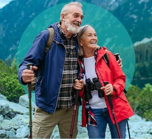 Elderly couple hiking with trekking poles in mountainous landscape