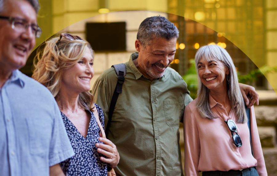 Two white senior couples walking down a city street and smiling